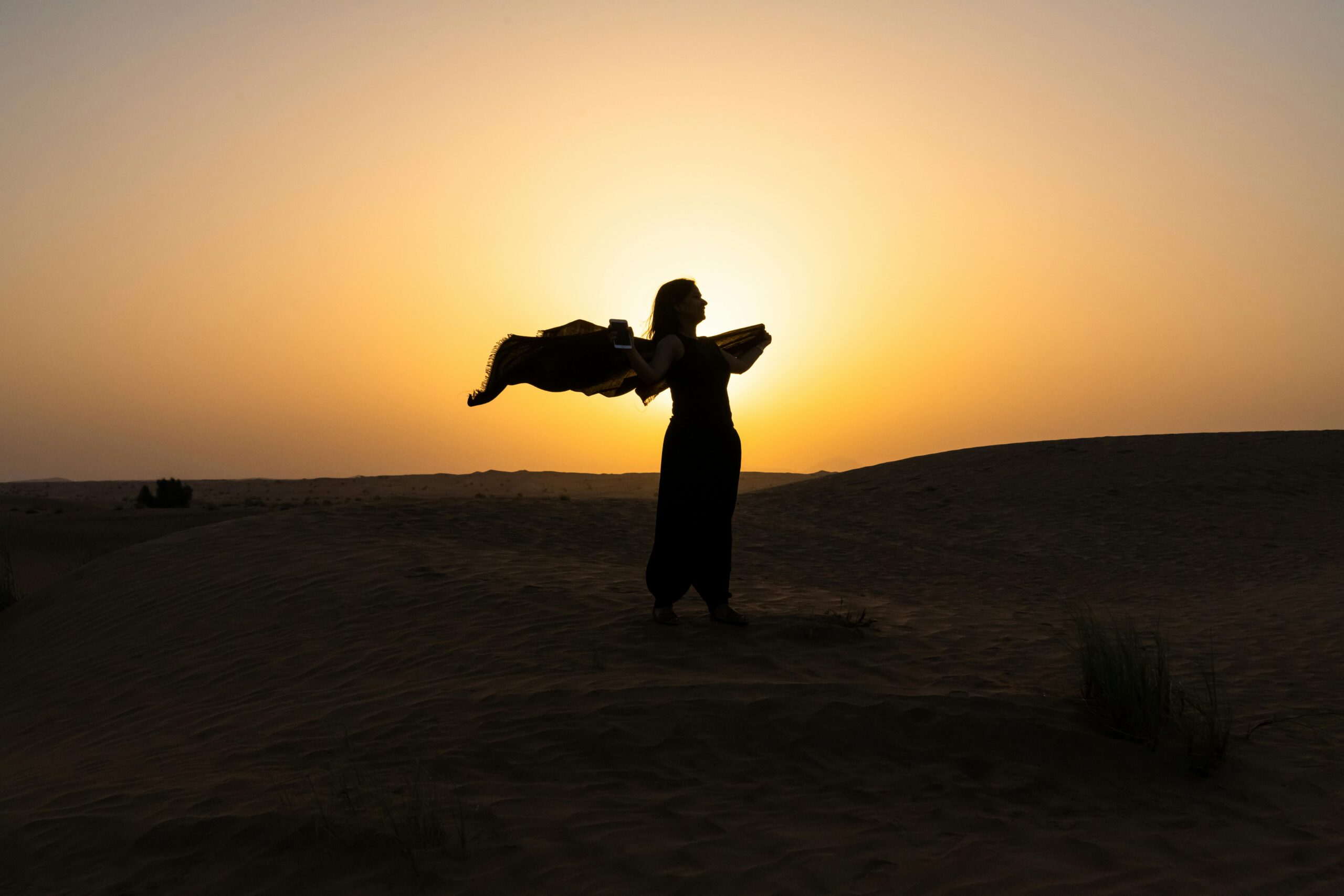 A serene morning desert landscape in Dubai with a 4x4 vehicle traversing the dunes.